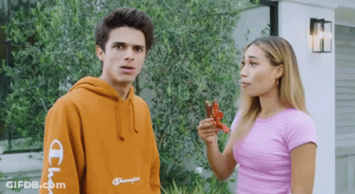 A Man Wearing An Orange Champion Hoodie Is Standing Next To A Woman In A Pink Shirt GIF