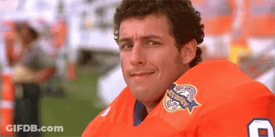 A Man Wearing An Orange Football Jersey Is Smiling . GIF