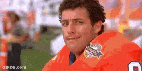 A Man Wearing An Orange Football Jersey With The Number 8 On It Is Looking At The Camera . GIF