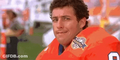 A Man Wearing An Orange Football Jersey With The Number 8 On It Is Looking At The Camera . GIF