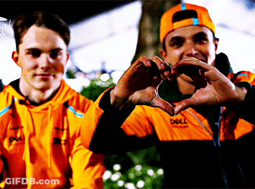 A Man Wearing An Orange Jacket That Says Dell Makes A Heart Shape With His Hands GIF