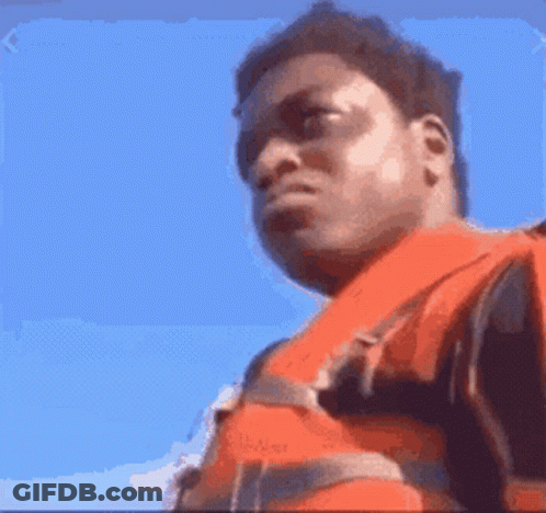 A Man Wearing An Orange Life Jacket Looks At The Camera With A Blue Sky In The Background GIF