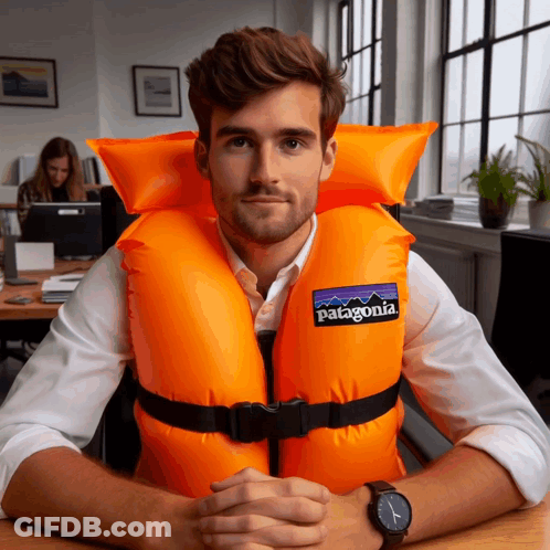 A Man Wearing An Orange Life Vest That Says Patagonia On It GIF