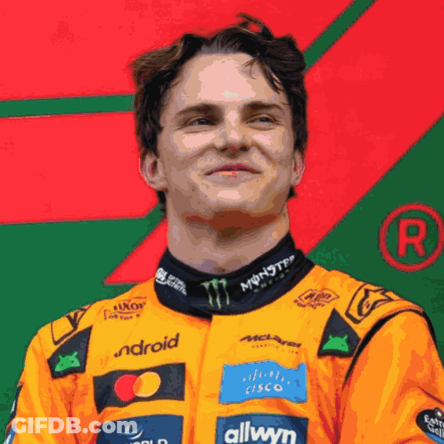 A Man Wearing An Orange Racing Suit With Monster Energy And Allwyn Logos GIF