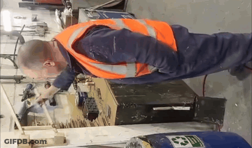 A Man Wearing An Orange Safety Vest Is Working On A Machine . GIF