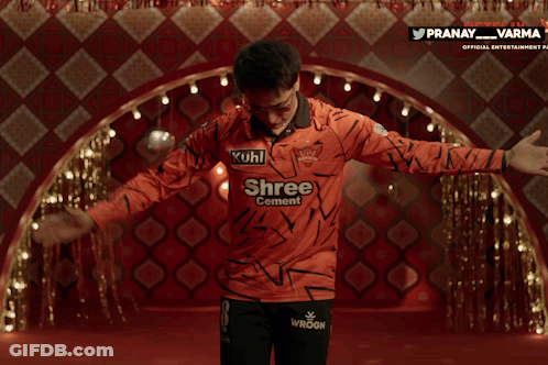 A Man Wearing An Orange Shirt That Says Kuhl Shree Central GIF
