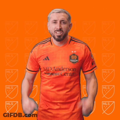 A Man Wearing An Orange Shirt That Says Manderson Soccer Center Holds His Fist In The Air GIF