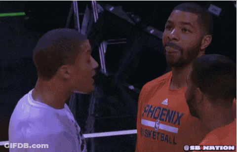 A Man Wearing An Orange Shirt That Says Phoenix Basketball Is Talking To Another Man GIF