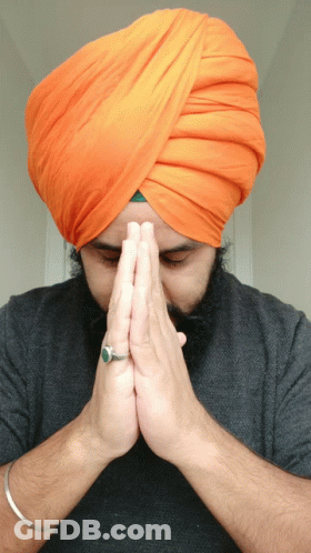 A Man Wearing An Orange Turban And A Ring On His Finger Prays GIF