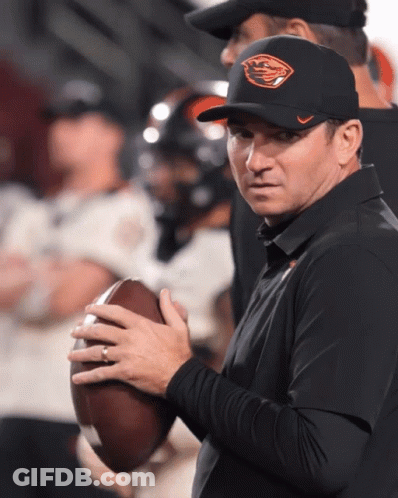 A Man Wearing An Oregon Hat Holds A Football In His Hands GIF