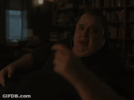 A Man Wearing An Oxygen Mask Is Sitting At A Table In Front Of A Bookshelf GIF