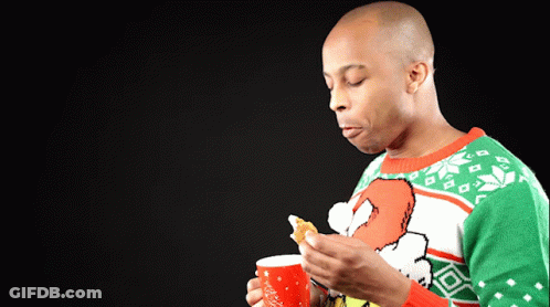 A Man Wearing An Ugly Christmas Sweater Is Holding A Cup Of Coffee GIF