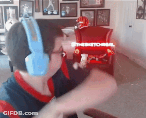 A Man Wearing Blue Headphones Is Sitting In Front Of A Chair That Says " Thesketchman " GIF