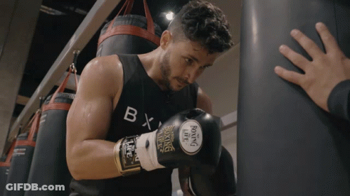 A Man Wearing Boxing Gloves And A Black Tank Top With The Letter B On It GIF