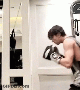 A Man Wearing Boxing Gloves Is Standing In Front Of A Mirror GIF