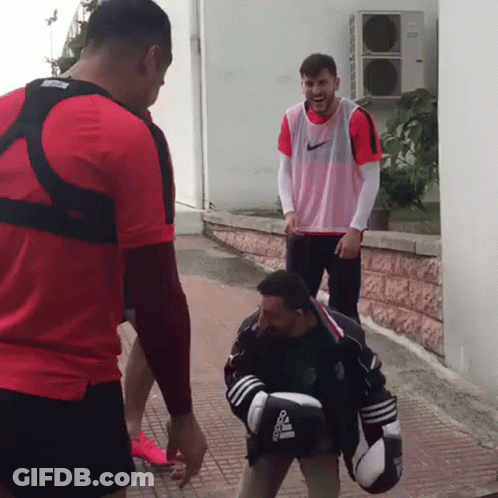 A Man Wearing Boxing Gloves That Say Adidas Is Standing Next To Another Man GIF
