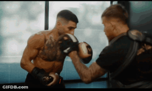 A Man Wearing Boxing Gloves With The Letter R On Them GIF