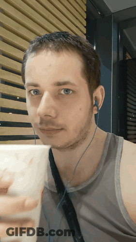A Man Wearing Ear Buds Is Holding A Cup Of Coffee GIF