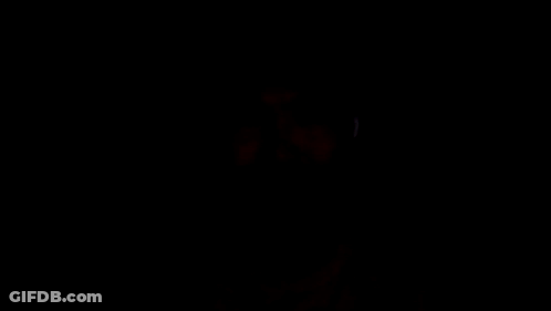 A Man Wearing Ear Buds Is Looking At The Camera In The Dark GIF