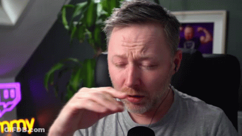 A Man Wearing Ear Buds Is Sitting In Front Of A Microphone And A Sign That Says Jimmy GIF