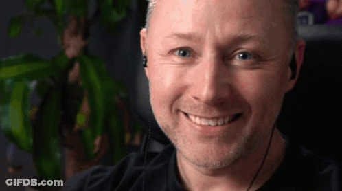 A Man Wearing Ear Buds Is Smiling For The Camera GIF