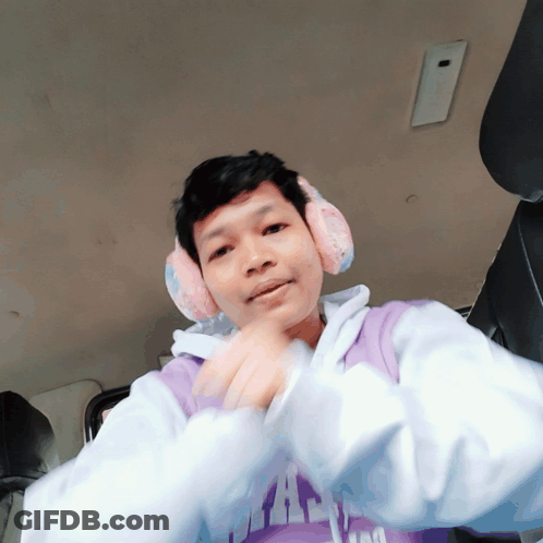 A Man Wearing Ear Muffs And A Purple Shirt That Says ' I Am ' On It GIF
