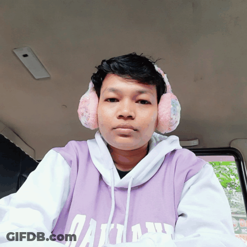 A Man Wearing Ear Warmers And A Purple Shirt That Says Dallas GIF