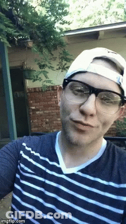 A Man Wearing Glasses A Hat And A Striped Shirt Takes A Selfie GIF