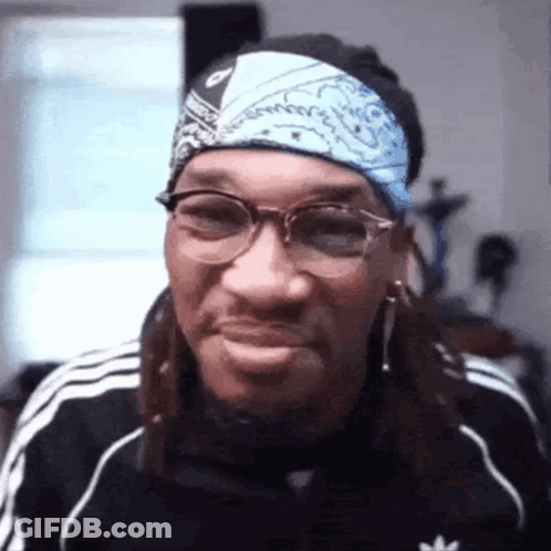 A Man Wearing Glasses And A Bandana Is Smiling And Making A Funny Face . GIF