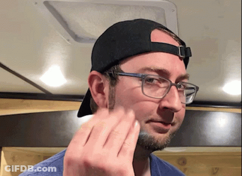 A Man Wearing Glasses And A Baseball Cap Wipes His Face GIF