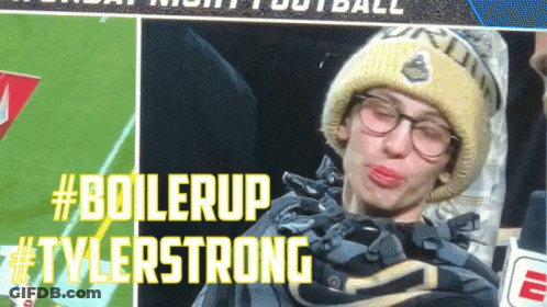A Man Wearing Glasses And A Beanie Is Making A Funny Face With #Boilerup Tylerstrong Written In Yellow Letters GIF