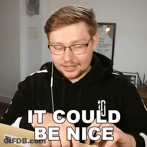 A Man Wearing Glasses And A Black Hoodie Is Holding A Piece Of Paper That Says It Could Be Nice GIF
