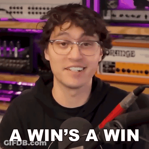 A Man Wearing Glasses And A Black Hoodie Says " A Win 'S A Win " In Front Of A Microphone GIF