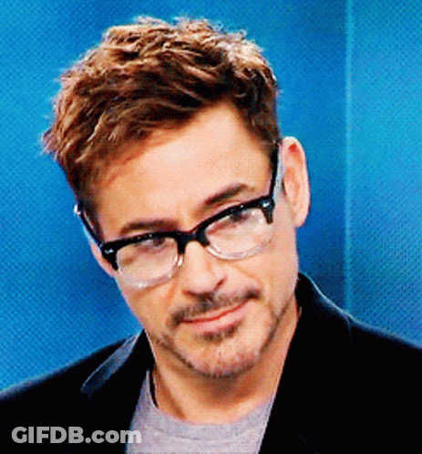 A Man Wearing Glasses And A Black Jacket Is Smiling GIF