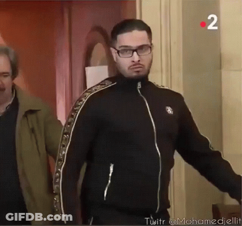 A Man Wearing Glasses And A Black Jacket With The Number 2 In The Corner GIF