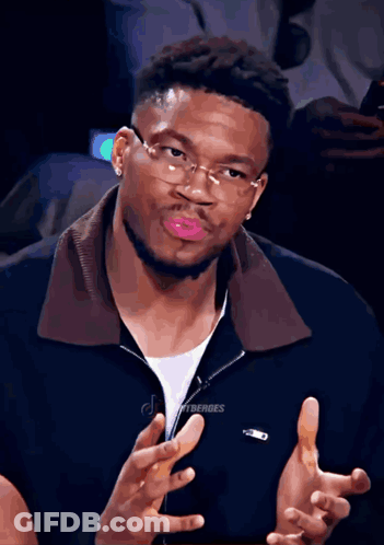A Man Wearing Glasses And A Black Jacket With The Word Lacoste On It GIF