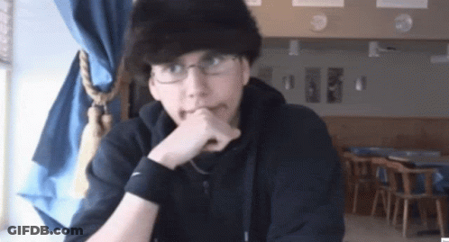 A Man Wearing Glasses And A Black Nike Wristband Is Sitting At A Table GIF