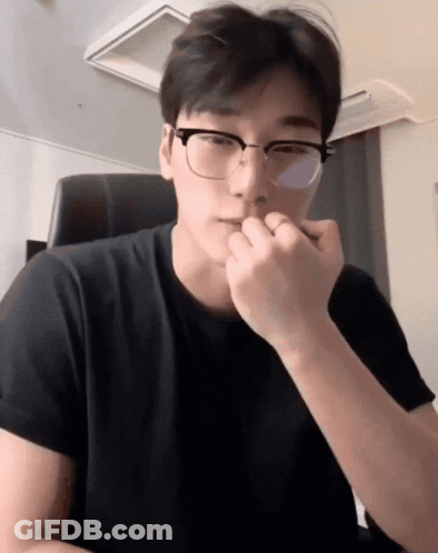 A Man Wearing Glasses And A Black Shirt Holds His Hand To His Chin GIF