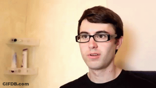 A Man Wearing Glasses And A Black Shirt Is Looking At The Camera GIF