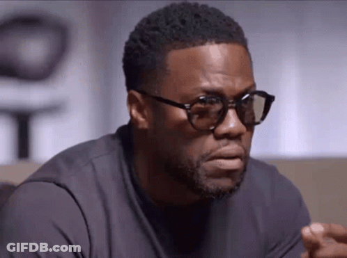 A Man Wearing Glasses And A Black Shirt Is Looking At The Camera . GIF