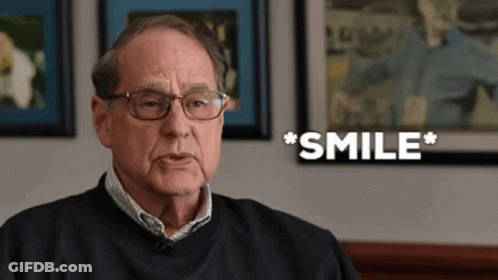 A Man Wearing Glasses And A Black Shirt Is Smiling GIF