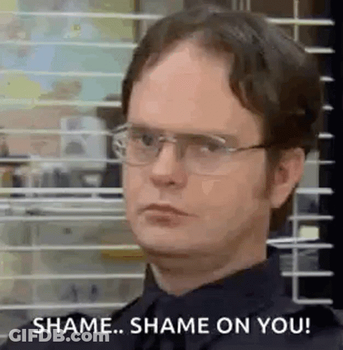 A Man Wearing Glasses And A Black Shirt Is Standing In Front Of A Window With Blinds . GIF