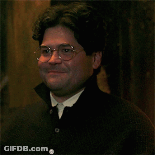 A Man Wearing Glasses And A Black Shirt Smiles For The Camera GIF