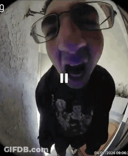 A Man Wearing Glasses And A Black Shirt With A Skull On It GIF