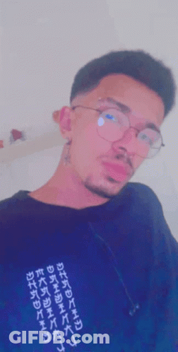 A Man Wearing Glasses And A Black Shirt With Chinese Writing GIF