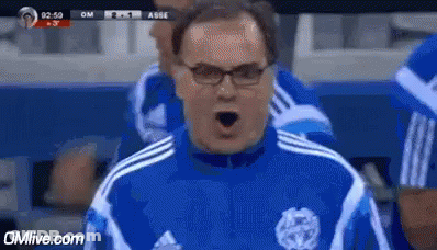 A Man Wearing Glasses And A Blue And White Adidas Shirt Is Shouting . GIF
