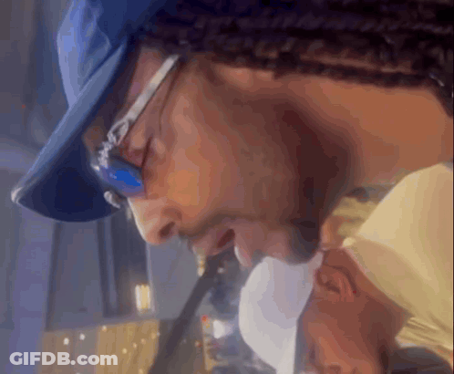 A Man Wearing Glasses And A Blue Hat Looks Down GIF