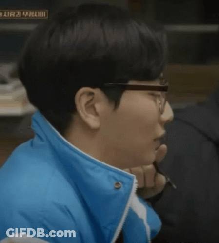 A Man Wearing Glasses And A Blue Jacket Has A Sign In The Background That Says ' A ' On It GIF