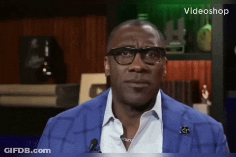 A Man Wearing Glasses And A Blue Jacket Is Sitting In Front Of A Microphone With The Word Videoshop On The Bottom GIF