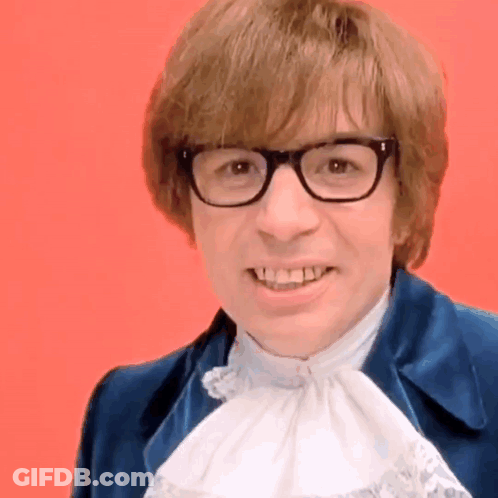 A Man Wearing Glasses And A Blue Jacket Smiles GIF